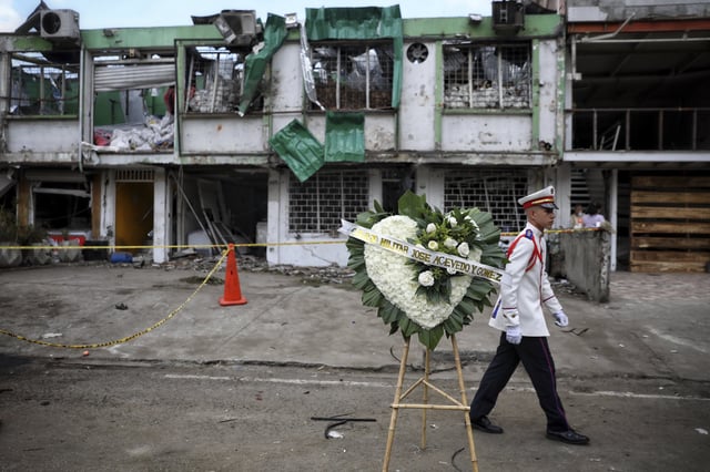 Un estudiante de una escuela militar camina después de colocar una corona en honor a las personas que fallecieron por la explosión de un coche bomba en Cali, Colombia, el viernes 22 de agosto de 2025