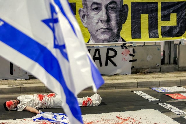 Un manifestant est allongé sur le sol, pour symboliser un otage israélien, lors d'une manifestation anti-gouvernementale organisée par les familles des Israéliens retenus en otages dans la bande de Gaza, le 23 août 2025