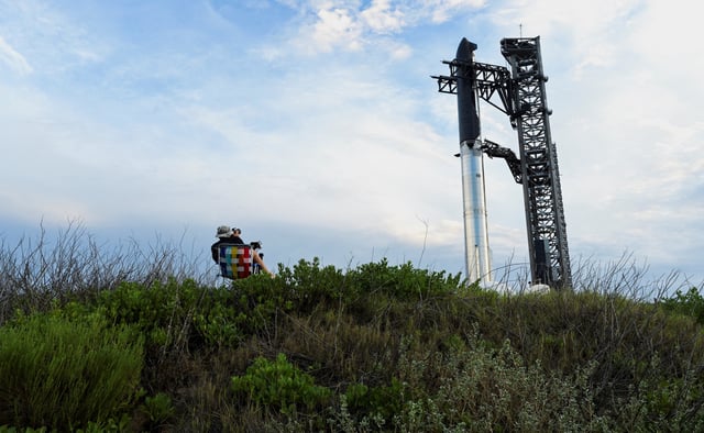 A photographer watches as the SpaceX Starship spacecraft is hoisted along the launch tower for stacking atop the heavy booster in preparation for its 10th test flight from the company's complex in Starbase, Texas, U.S., August 23, 2025. REUTERS/Steve Nesius