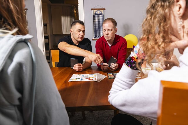 Calder Storm, left, Tristan Storm and their children play a family board game on Friday in San Francisco.
