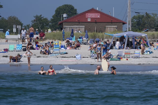 Visitors enjoy the summer weather not far from recent sightings of white sharks, Wednesday, Aug. 13, 2025, in Scarborough, Maine. (AP Photo/Robert F. Bukaty)