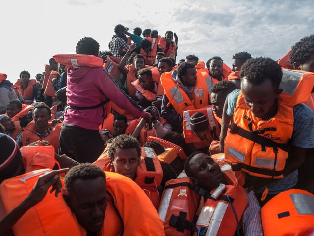 LAMPEDUSA, ITALY - MAY 24: Refugees and migrants put on life jackets distributed by rescue crews of the Migrant Offshore Aid Station (MOAS) 'Phoenix' vessel on May 24, 2017 off Lampedusa, Italy. The boat, one of three in the area later capsized killing more than 30 people, crewmembers from the 'Phoenix' rescued 603 people. Numbers of refugees and migrants attempting the dangerous central Mediterranean crossing from Libya to Italy has risen since the same time last year with more than 43,000 people recorded so far in 2017. In an attempt to slow the flow of migrants Italy recently signed a deal with Libya, Chad and Niger outlining a plan to increase border controls and add new reception centers in the African nations, which are key transit points for migrants heading to Italy. MOAS is a Malta based NGO dedicated to providing professional search-and-rescue assistance to refugees and migrants in distress at sea. Since the start of the year MOAS have rescued and assisted 3572 people and are currently patrolling and running rescue operations in international waters off the coast of Libya. (Photo by Chris McGrath/Getty Images)