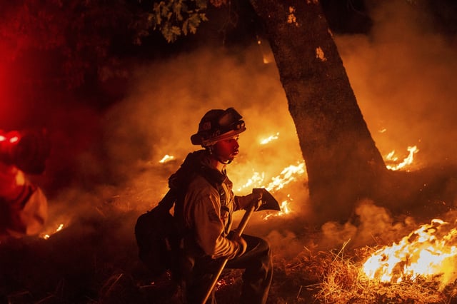 A firefighter battles the Pickett Fire burning in the Aetna Springs area of Napa County, Calif., on Saturday, Aug. 23, 2025.