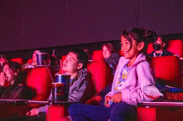 Families and fans show up for the Netflix singalong screening of "Kpop Demon Hunters" at Regal Stonestown Galleria in San Francisco. Some attendees wore costumes and accessories that referenced the fictional K-pop groups, whose songs are a real life hit.