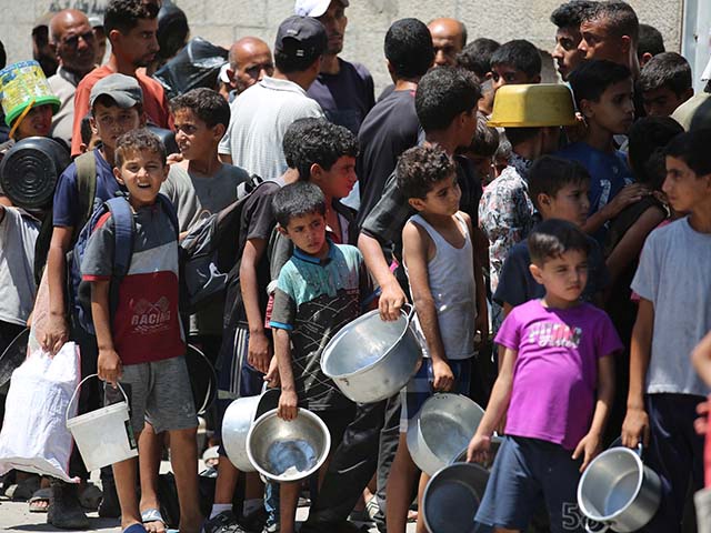 Palestinians, including children, who are struggling to access food due to Israel's blockade and ongoing attacks on the Gaza Strip, receive hot meals distributed by the charity organization at Nuseirat refugee camp in Gaza City, Gaza on August 23, 2025. (Photo by Hassan Jedi/Anadolu via Getty Images)