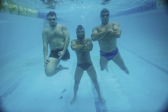 Ukrainian war veterans Oleksandr Dashko, from left, Oleh Tserkovnyi and Pavlo Tovstyk, pose for an underwater photo in a pool in Kyiv, Ukraine, Tuesday, Aug. 12, 2025, as they take a break from their training session for the upcoming 6.5km swimming race across the Bosporus Strait. (AP Photo/Evgeniy Maloletka)