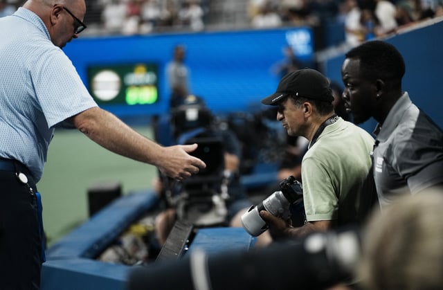 Tennis - U.S. Open - Flushing Meadows, New York, United States - August 24, 2025 A staff member escorts a photographer out during the match between France's Benjamin Bonzi and Russia's Daniil Medvedev REUTERS/Eduardo Munoz