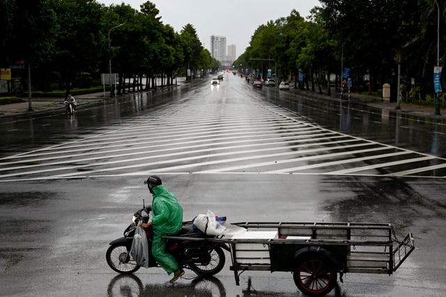 A man rides a motorbike on a road before Typhoon Kajiki makes landfall in Vietnam, in Nghe An province on August 25, 2025. Vietnam said on August 24 it plans to evacuate more than 300,000 people and has cancelled over a dozen domestic flights as Typhoon Kajiki approaches.