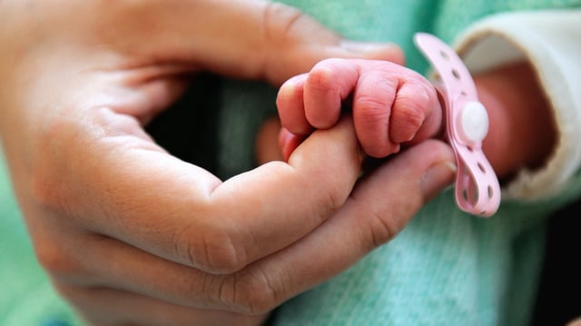 A newborn takes the finger of his mother in a hospital in France.