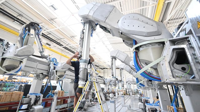 Ein Arbeiter des Maschinenbauers Dürr montiert  einen Roboterarm.