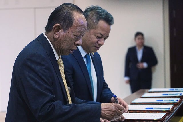 Cambodian lawmaker Tea Banh, left, registers together with his son, Deputy Prime Minister and Minister of National Defense Tea Seiha, center, before the session on the draft law on amending the law on nationality at the National Assembly in Phnom Penh Cambodia, Monday, Aug. 25, 2025. (AP Photo/Heng Sinith)