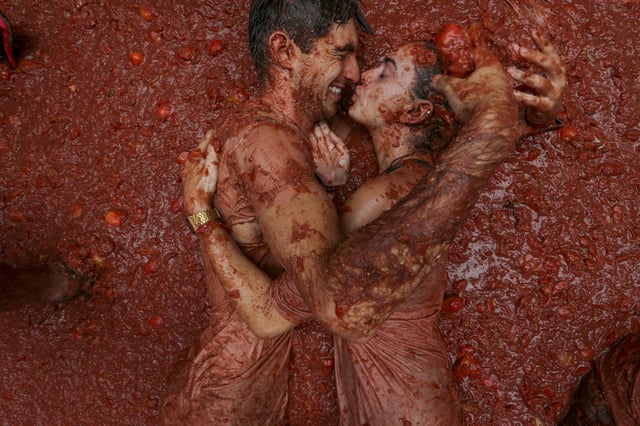 FILE - Revelers lie in a pool of squashed tomatoes during the annual "Tomatina" tomato fight fiesta, in Bunol, near Valencia, Spain, Aug. 28, 2024. (AP Photo/Alberto Saiz, File)