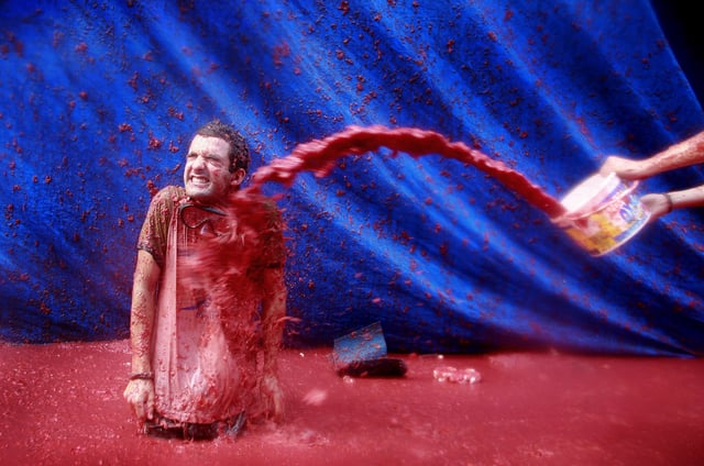 FILE - A reveler throws tomato pulp at another during the annual food fight, the Tomatina, in Bunol, near Valencia, Spain, Aug. 27, 2008. (AP Photo/Fernando Bustamante, File)