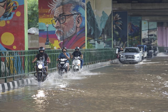 Commuters move through a flooded road after heavy rain in Jammu, India, Sunday, Aug. 24, 2025.(AP Photo/Channi Anand)