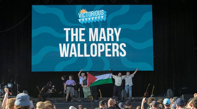 Róisín "Mary" Barrett, Charles Hendy, Andrew Hendy and Ken Mooney of The Mary Wallopers wave a Palestinian flag on the stage of the Victorious festival after their microphones were cut, Aug. 22, 2025 in Southsea, England. (Mark Holloway/Redferns via Getty Images)