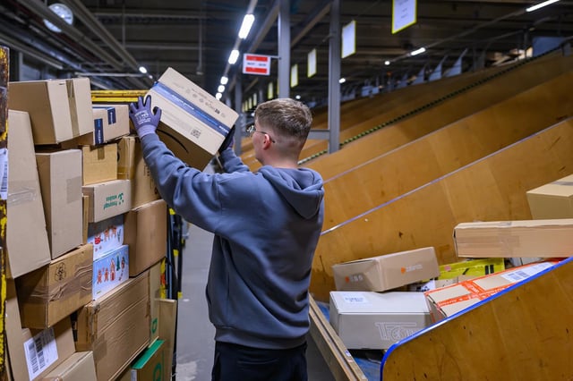 An employee loads a trolley with packages at the DHL parcel center in Brandenburg, Germany, in 2024.  