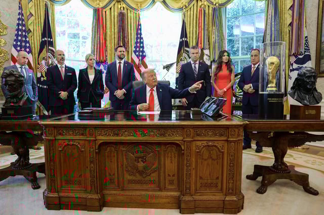 U.S. President Donald Trump points to the FIFA World Cup Trophy during an event in the Oval Office to sign an executive order, at the White House in Washington, D.C., U.S., August 25, 2025. REUTERS/Jonathan Ernst