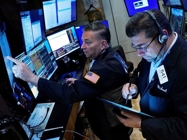 Traders Jonathan Mueller, left, and Michael Capolino work on the floor of the New York Stock Exchange, Monday, Nov. 1, 2021. Stocks are opening modestly higher on Wall Street Monday, bringing major indexes a bit further past the record highs they set last week. (AP Photo/Richard Drew)