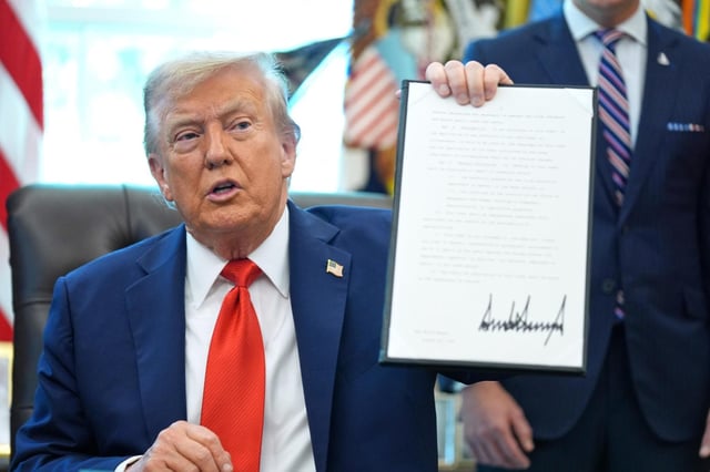 El presidente Donald Trump sostiene una orden ejecutiva firmada que requiere que el Departamento de Justicia investigue los casos de quema de banderas, en la Oficina Oval de la Casa Blanca, el lunes 25 de agosto de 2025, en Washington. (AP Foto/Evan Vucci)
