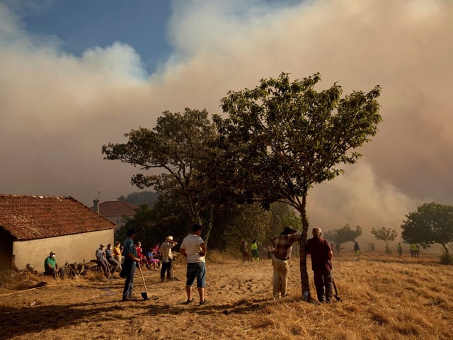 Residents and firefighters battle a fire advancing toward Rebordondo village, near Ourense, in northwestern Spain, on Monday, Aug. 18, 2025. (AP Photo/Pablo Garcia)