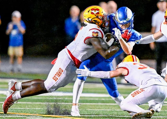 Jake Martin (13) of Santa Margarita takes a hard hit from Jayden Hill (5) of Mission Viejo in the season-opening game at Trabuco Hills High School in Mission Viejo on Friday, Aug. 22, 2025. (Photo by Leonard Ortiz, Orange County Register/SCNG)