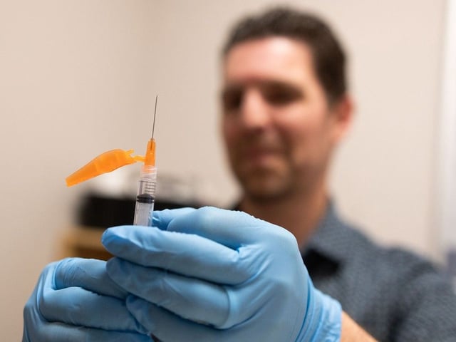 Pharmacist Randy Howden administers a COVID-19 vaccine at the Medicine Shoppe Pharmacy in the Crowfoot West Business Centre in Calgary on Oct. 16, 2024. This coming season, shots will be only be available through government clinics.