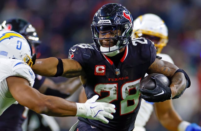 Joe Mixon #28 of the Houston Texans carries the ball on a running play in front of Daiyan Henley #0 of the Los Angeles Chargers for a touchdown during the second half of the AFC Wild Card Playoff game at NRG Stadium on January 11, 2025 in Houston, Texas.