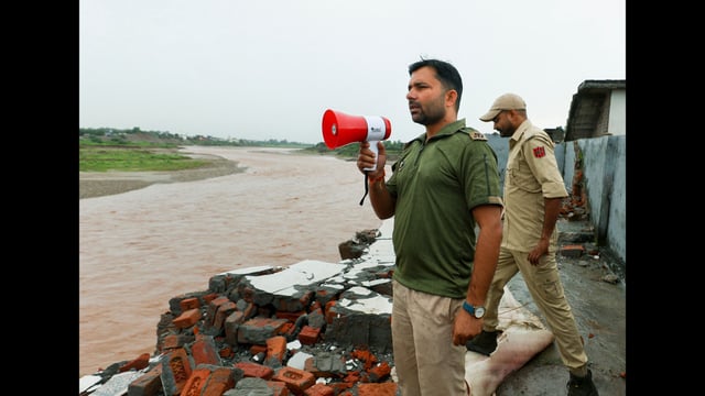 Police personnel prepare to warn and evacuate people from near Tawi river following heavy rainfall, in Jammu, on Monday. (PTI)