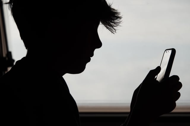 In this photo illustration, a 13-year-old boy looks at an iPhone screen on May 26, 2025 in Penzance, England.