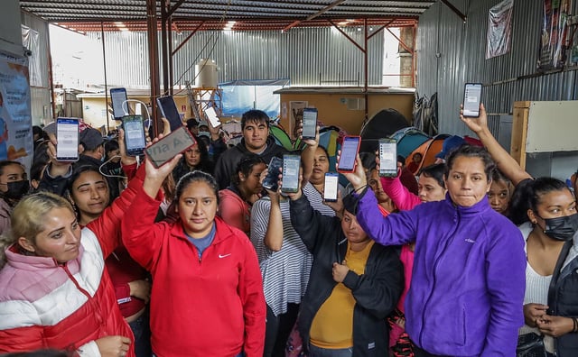 Migrantes que residen en el albergue Movimiento Juventud 2000 muestran en su celular cómo ha dejado de funcionar la aplicación CBP One que daba citas para solicitar asilo en EEUU, en Tijuana, Baja California (México)