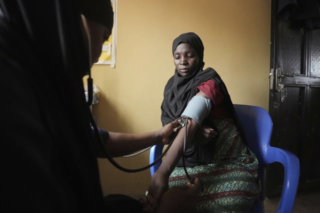 A midwife checks a Falmata Muhammed's blood pressure at a facility run by aid agency International Rescue Committee, in Magumeri, in northeast Nigeria's Borno state, Tuesday, July 22, 2025. (AP Photo/Sunday Alamba)