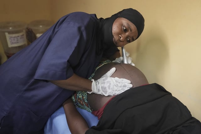 A midwife checks a pregnant woman at a facility run by aid group International Rescue Committee, in Magumeri, in northeast Nigeria's Borno state, Tuesday, July 22, 2025. (AP Photo/Sunday Alamba)