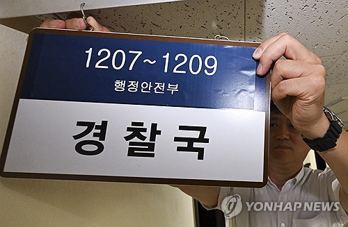 An interior ministry official takes down the signboard of the ministry's Police Bureau at the Seoul Government Complex on Aug. 26, 2025. (Pool photo) (Yonhap)