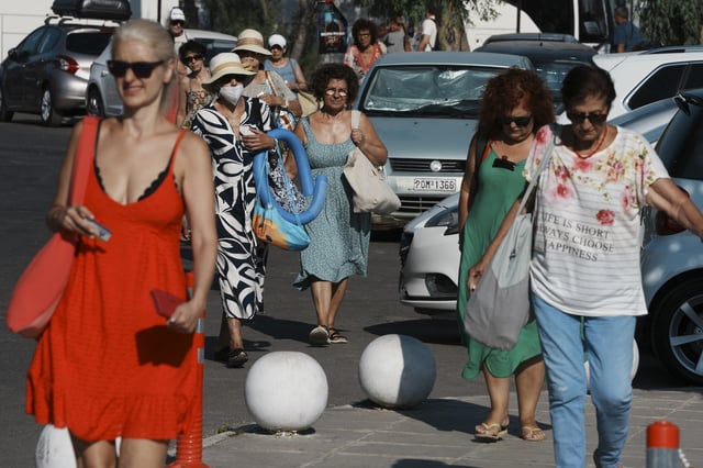 People arrive by bus at Avlaki beach about 42 kilometers (26 miles) east of Athens, Greece, Wednesday, Aug. 19, 2025. (AP Photo/Thanassis Stavrakis)