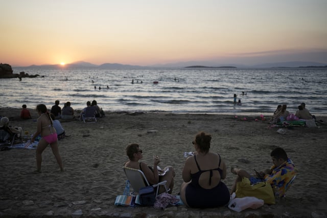People gather at Kavouri beach as the sun sets in southern Athens, Greece, Monday, Aug. 11, 2025. (AP Photo/Thanassis Stavrakis)