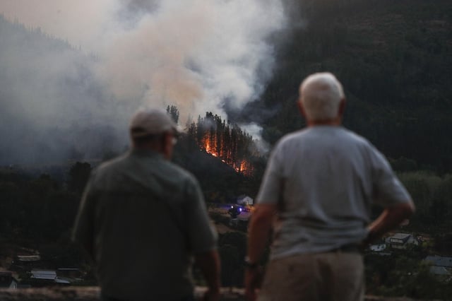 Dos residentes observan una zona forestal en llamas cerca del pueblo de Quiroga, en Lugo.