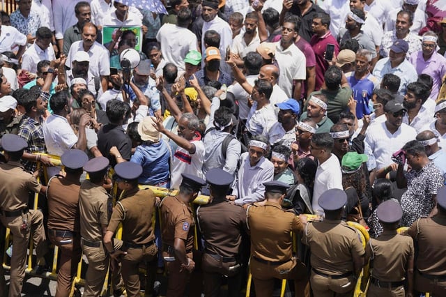 Supporters of arrested former president Ranil Wickremesinghe shout slogans during a protest out side a magistrate's court in Colombo, Sri Lanka, Tuesday, Aug.26, 2025.(AP Photo/Eranga Jayawardena)