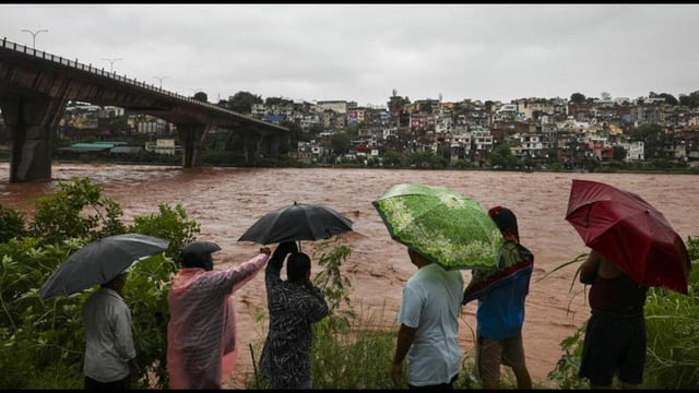 People near the Tawi river that is in spate amid rainfall in Jammu on Tuesday. The river has crossed the 20-ft danger mark in Udhampur district, while downstream in Jammu it is flowing below the alert level, officials said. (PTI Photo)
