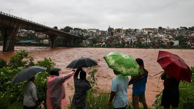 People look at the swollen Tawi river amid rainfall, in Jammu, Tuesday, Aug. 26, 2025.