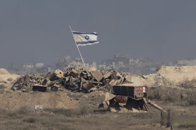 An Israeli flag waves over debris in an area of the Gaza Strip, as seen from southern Israel, Tuesday, Aug. 26, 2025. (AP Photo/Maya Levin)