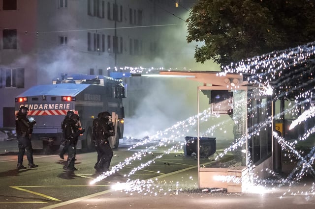 Feuerwerkskörper explodieren in der Nähe von Polizisten in Kampfausrüstung