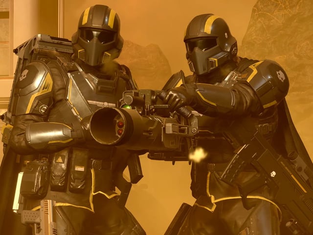 Two Helldivers using a team reload maneuver in battle.