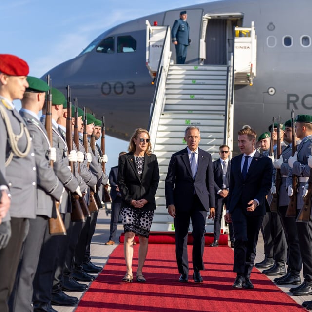 Prime Minister Mark Carney is met by a welcoming committee as he disembarks a government plane in Berlin on Aug. 25.
