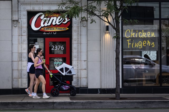 Pedestrians walk by a Raising Cane's restaurant on June 30, 2025, in Chicago, Illinois.