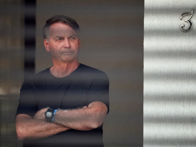 FILE PHOTO: Brazil's former President Jair Bolsonaro stands at his home while under house arrest, ordered by Supreme Court Justice Alexandre de Moraes, as he awaits trial over an alleged plot to overturn the 2022 election, in Brasília, Brazil, August 14, 2025. REUTERS/Adriano Machado/File Photo