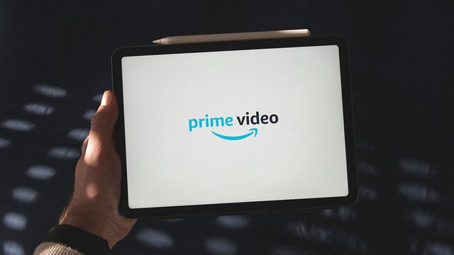 A man holding a tablet with a Prime Video logo