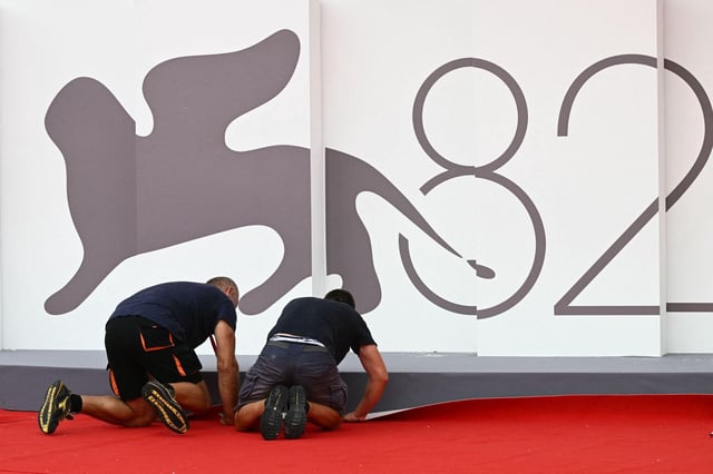 Dos operarios fijan la alfombra roja en el Palazzo del Cinema del Lideo de Venecia a las puertas de la 82ª edición de la Mostra