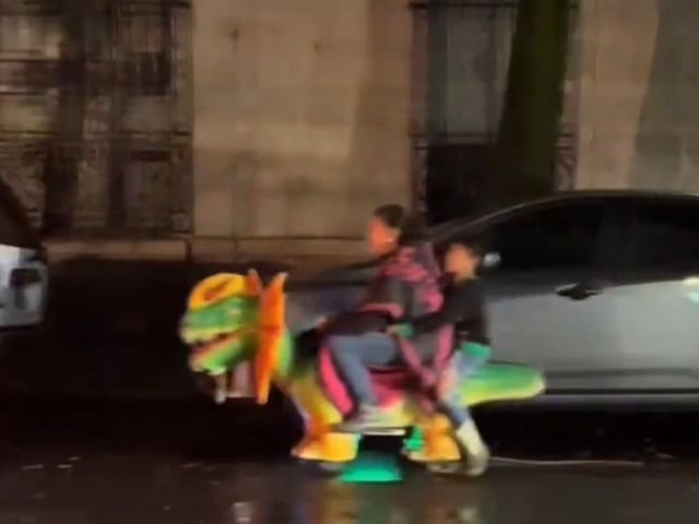 Mujer y niño circulan en dinosaurio eléctrico por las calles de la CDMX