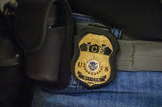 A federal agent wears a badge of Immigration and Customs Enforcement while standing outside an immigration courtroom at the Jacob K. Javits Federal Building in New York, on June 10, 2025.