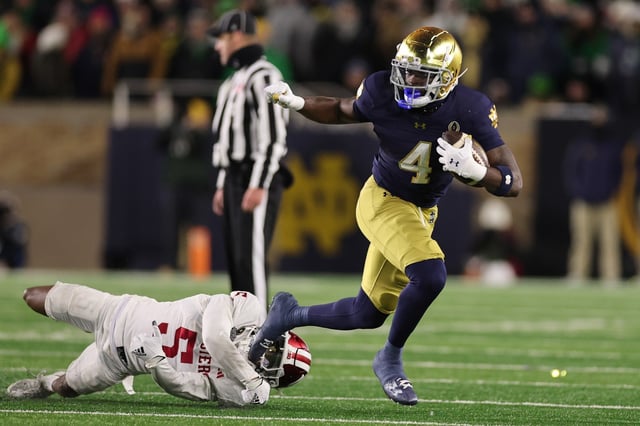 Jeremiyah Love (No. 4) of the Notre Dame Fighting Irish breaks a tackle from D'Angelo Ponds (No. 5) of the Indiana Hoosiers during the third quarter in the Playoff First Round game at Notre Dame Stadium on Dec. 20, 2024 in South Bend, Indiana. Love and Notre Dame face Miami in the season-opener on Sunday. (Photo by Michael Reaves/Getty Images)